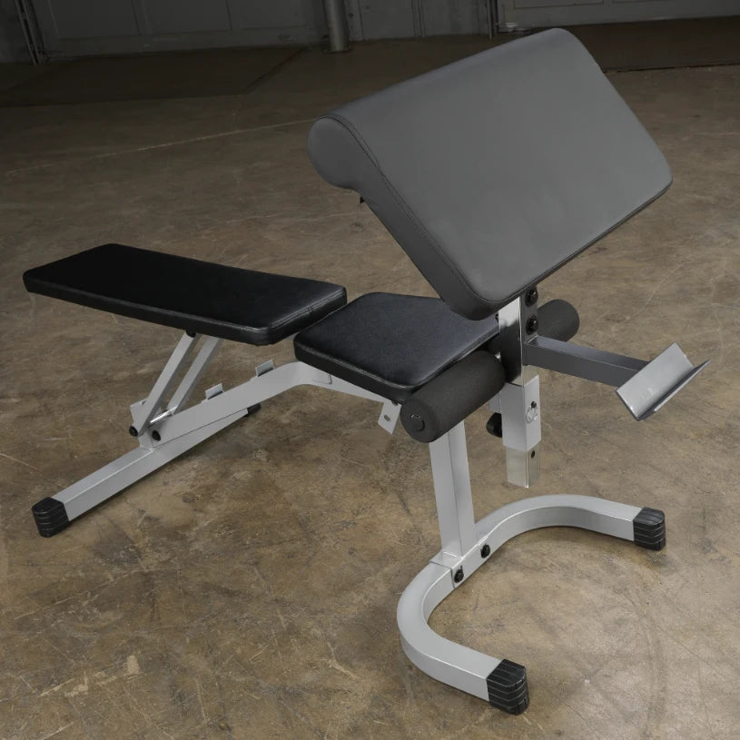 A black and silver adjustable workout bench positioned on a concrete floor, designed for strength training exercises.