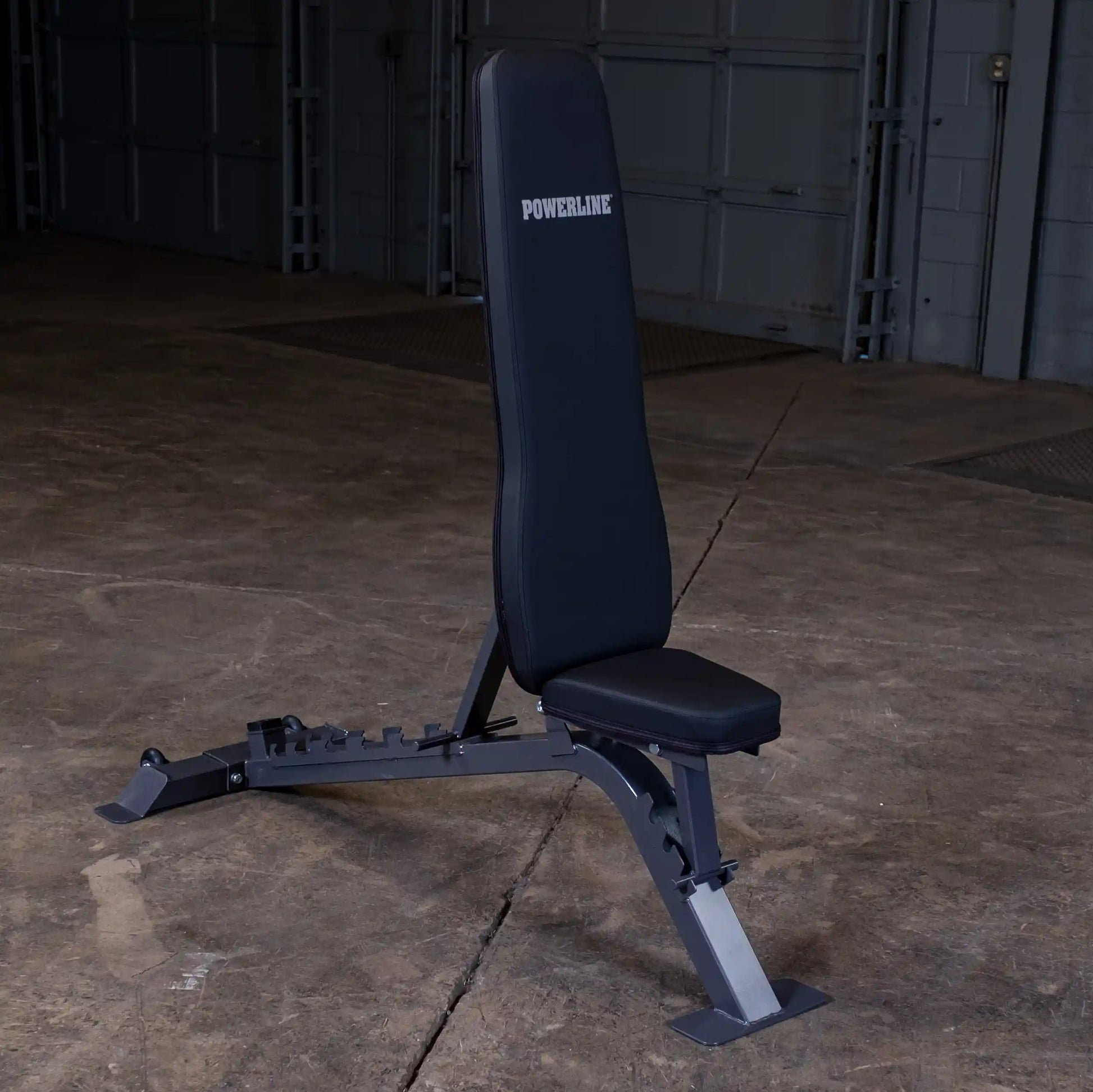 Powerline adjustable weight bench with a black padded seat and backrest, set against a concrete floor and garage background.