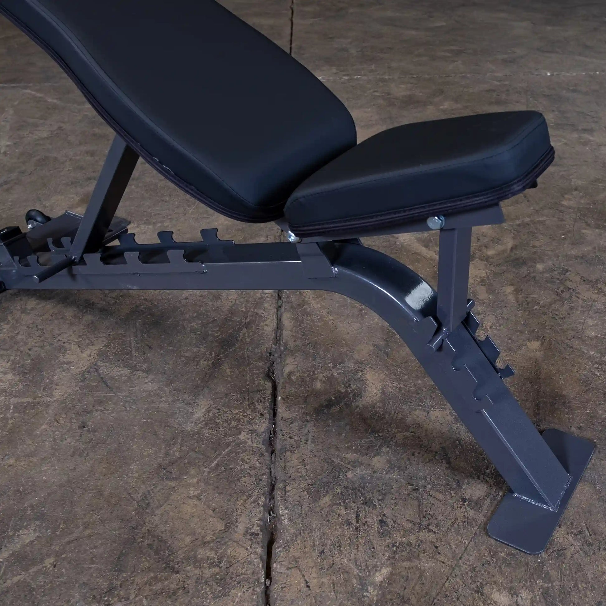 Adjustable weight bench with a padded seat and backrest, positioned on a concrete floor.
