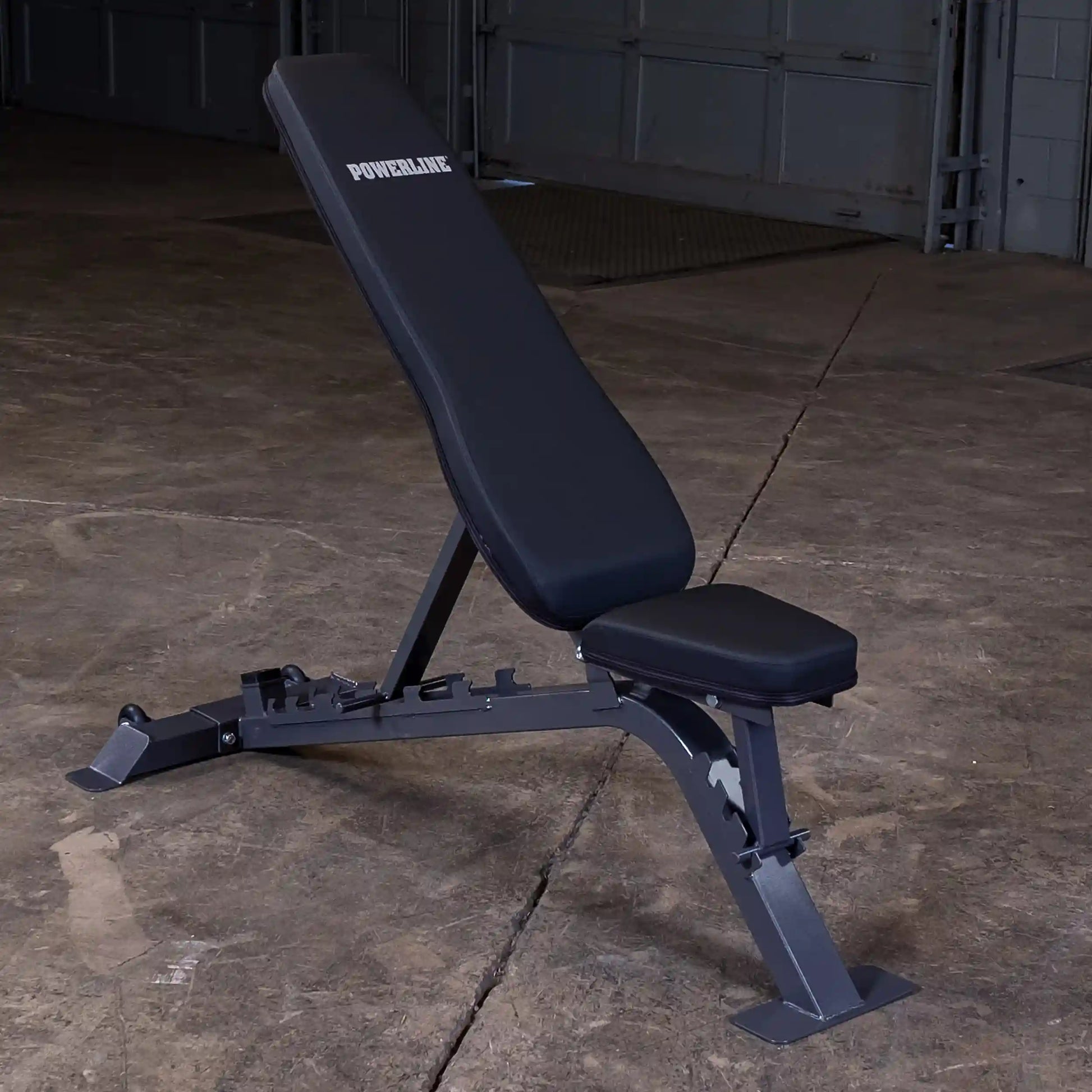 Adjustable weight bench by Powerline, featuring a sturdy metal frame and padded seating, positioned on a concrete floor in a gym environment.