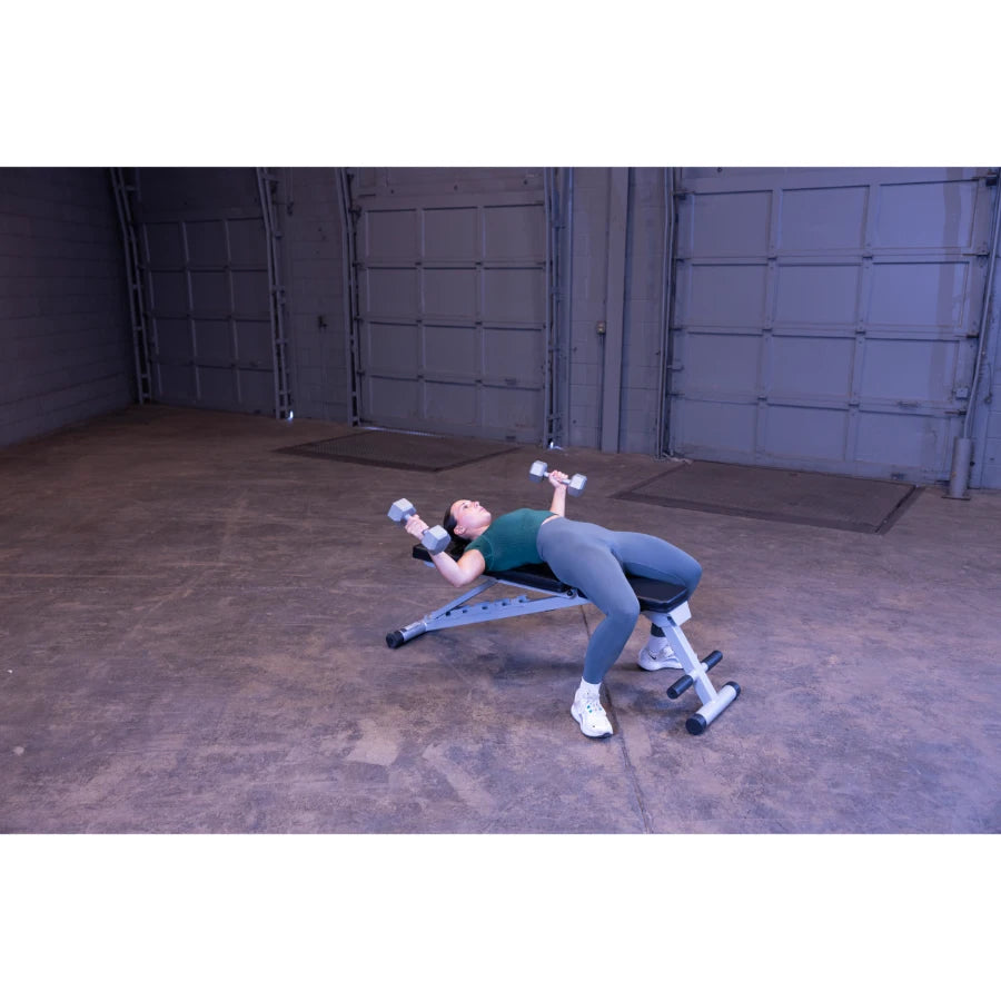 A person performing a dumbbell exercise on a workout bench in a spacious indoor gym setting.