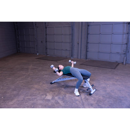 A person performing a dumbbell exercise on a workout bench in a spacious indoor gym setting.