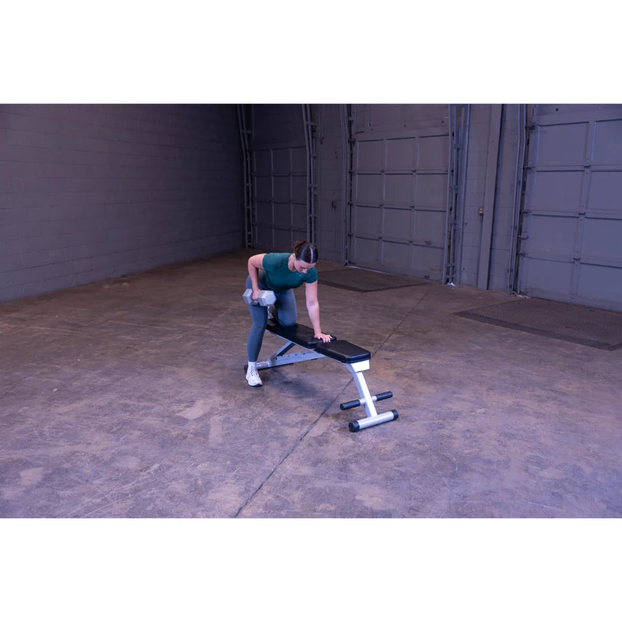A person performing a single-arm dumbbell row exercise on a workout bench in a spacious gym setting.