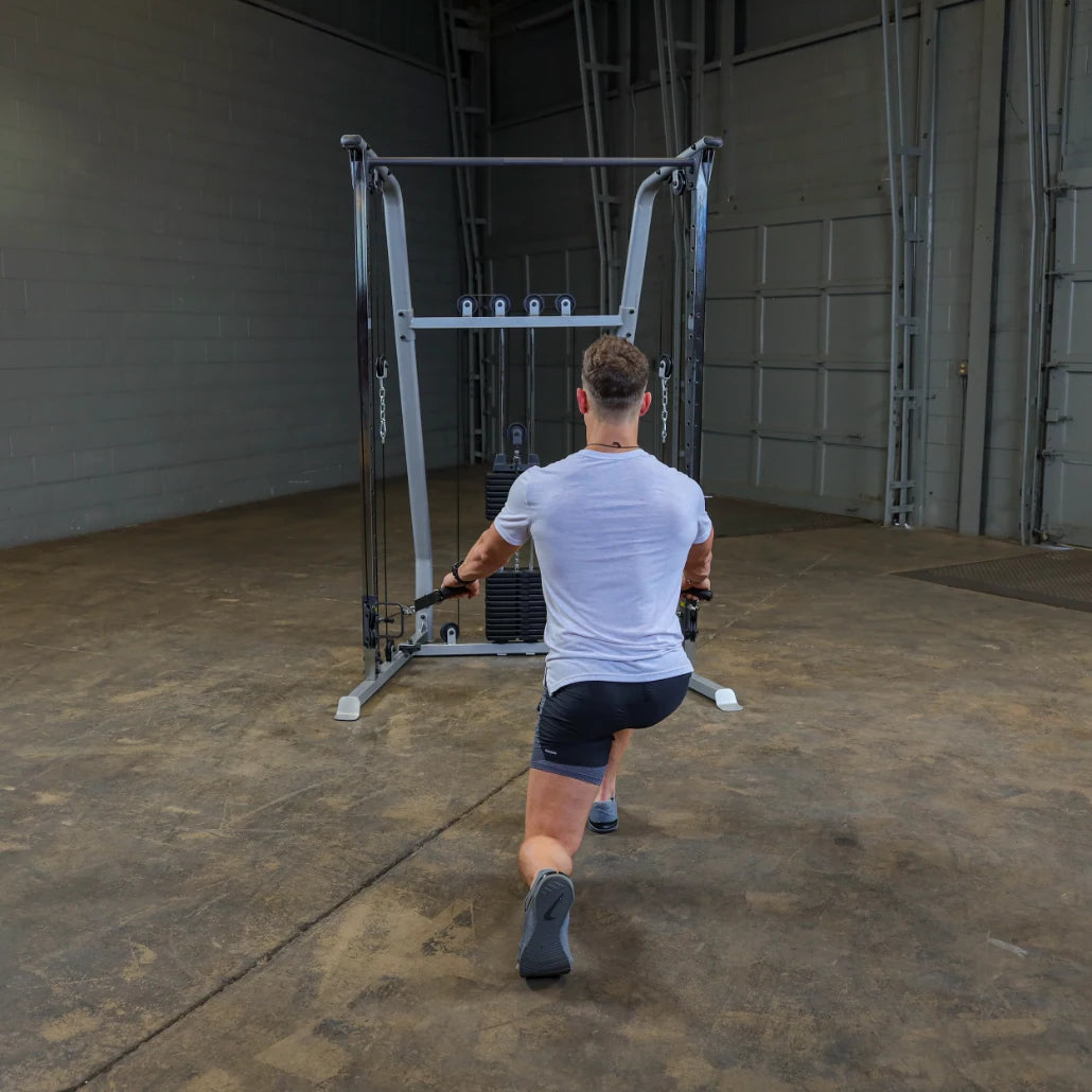 A person in athletic wear performing a cable exercise in a gym, facing away from the camera, with a cable machine in the background.