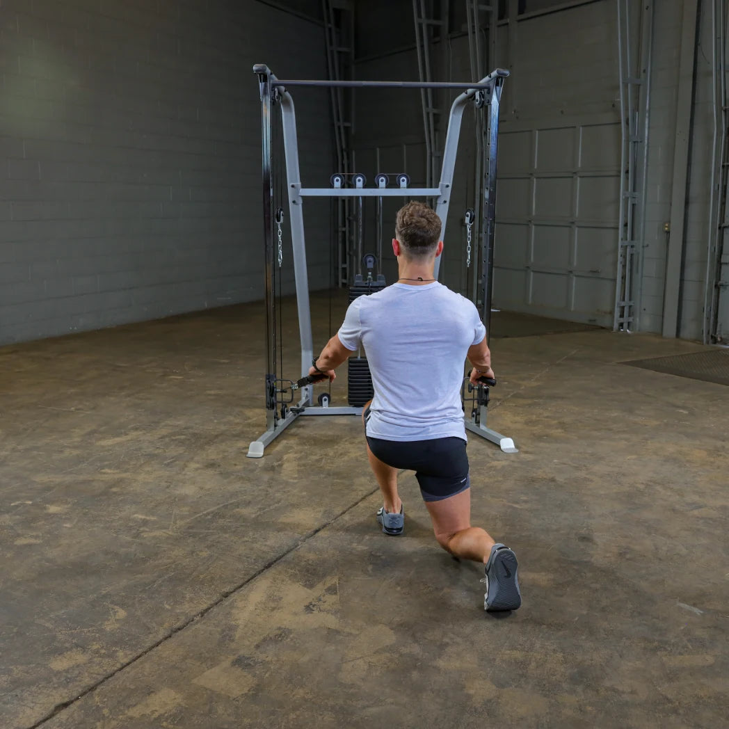 A person performing a lunge exercise while using a cable machine in a gym setting.