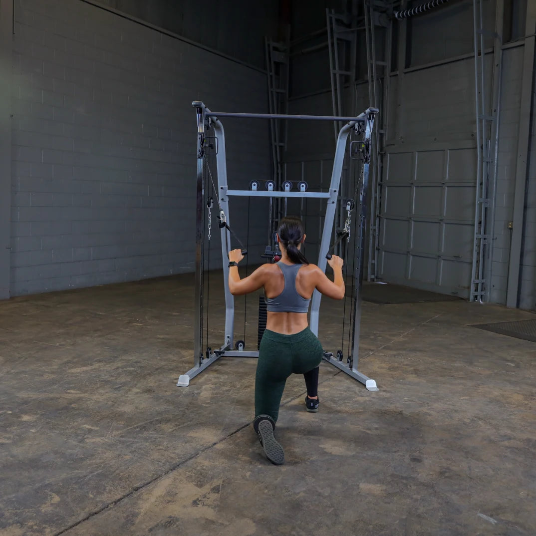 A person performing a lunge exercise using a cable machine in a gym setting, wearing a sports bra and leggings, with a focus on strength training.