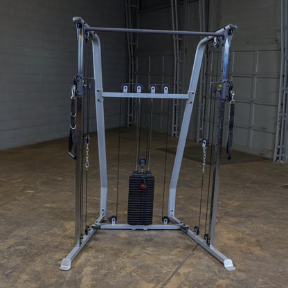 A multi-functional cable machine for strength training, featuring adjustable pulleys and a weight stack, set in a gym environment with a concrete floor and gray walls.