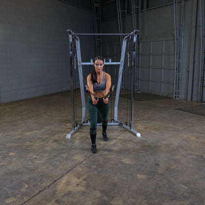 A person performing a cable exercise in a gym setting, using a cable machine with a focused expression while wearing athletic clothing.