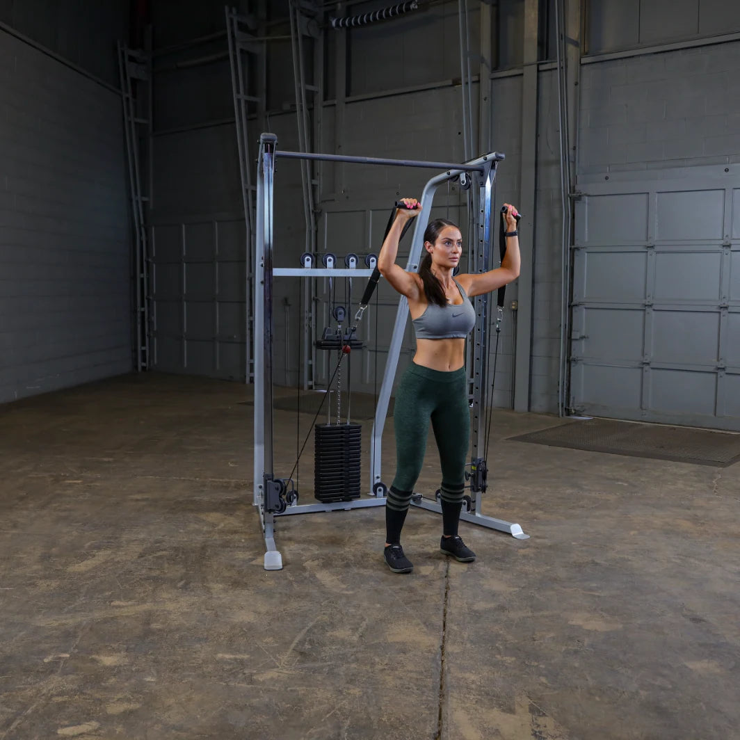 A woman performing an exercise using a cable machine in a gym setting, wearing a sports bra and green leggings, with a focus on strength training.