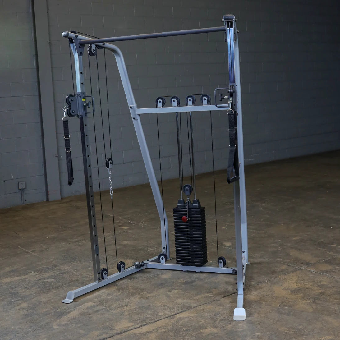 A multi-functional cable machine for strength training, featuring adjustable pulleys and a stack of weights, set against a plain wall in a gym environment.