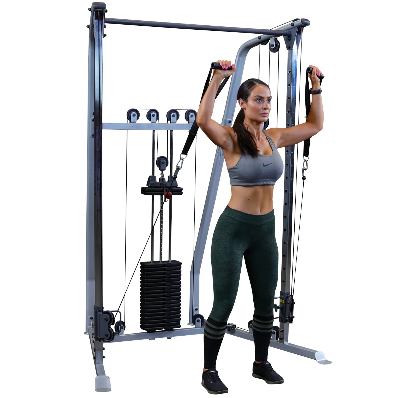 A woman in athletic wear using a cable machine for strength training, performing an exercise with resistance bands attached to the machine.
