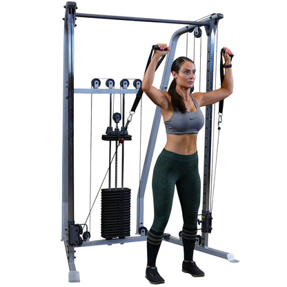 A woman in athletic wear using a cable machine for strength training, performing an exercise with resistance bands attached to the machine.