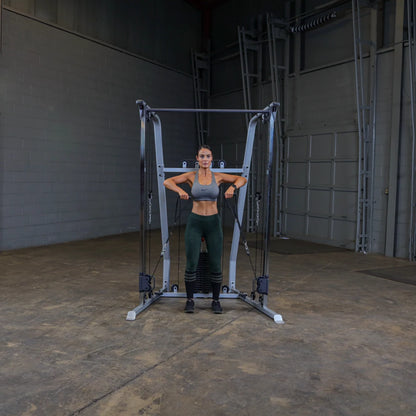 A woman in athletic wear performs an exercise using a cable machine in a gym setting, demonstrating strength training with her arms extended.