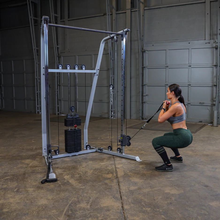 A woman performing a squat while using a cable machine in a gym setting, showcasing strength training exercises.