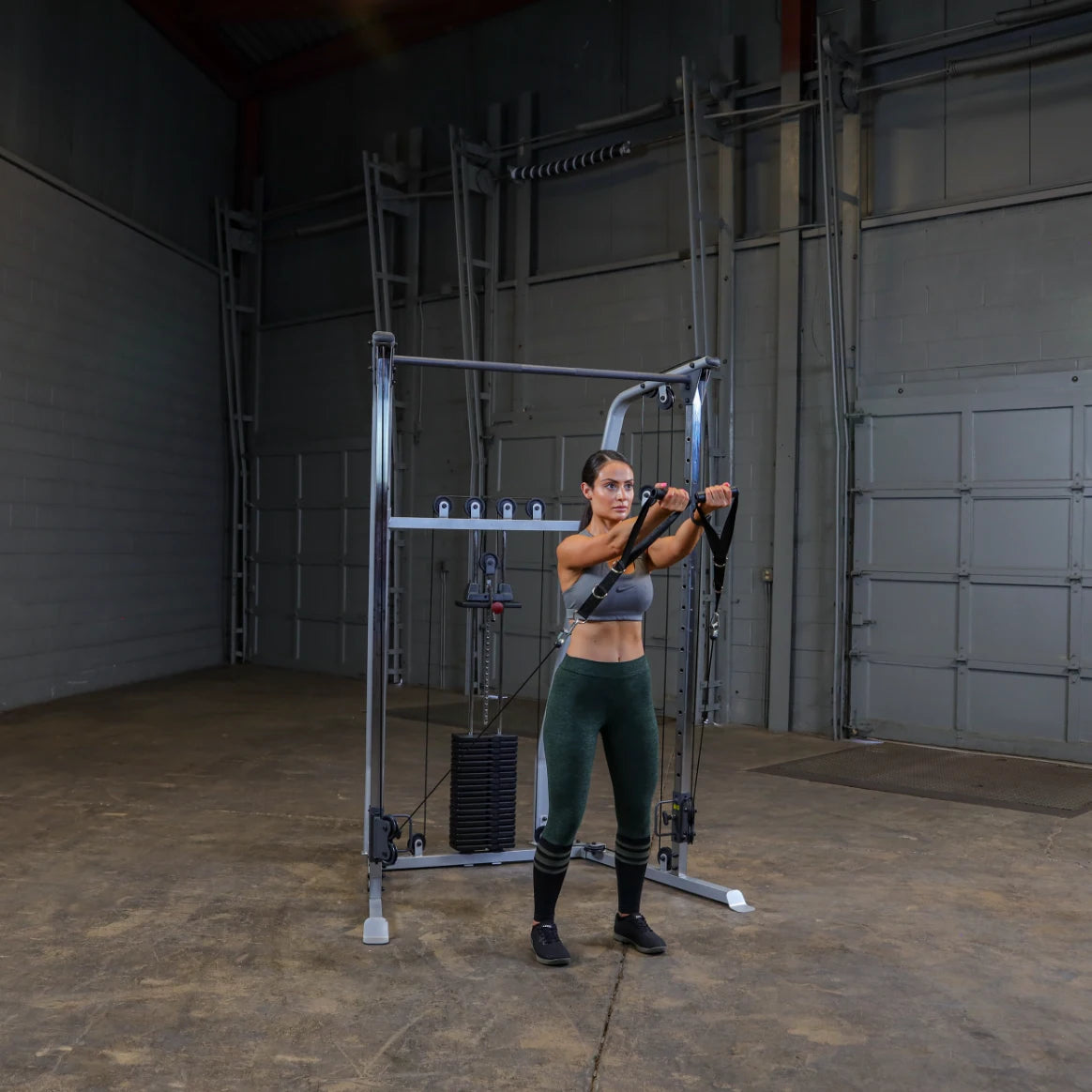 A woman in athletic wear performing an exercise using a cable machine in a spacious gym environment.