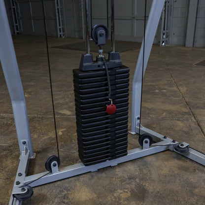 Close-up of a weight stack on a cable machine in a gym, featuring a black rectangular weight plate with a red adjustment knob.