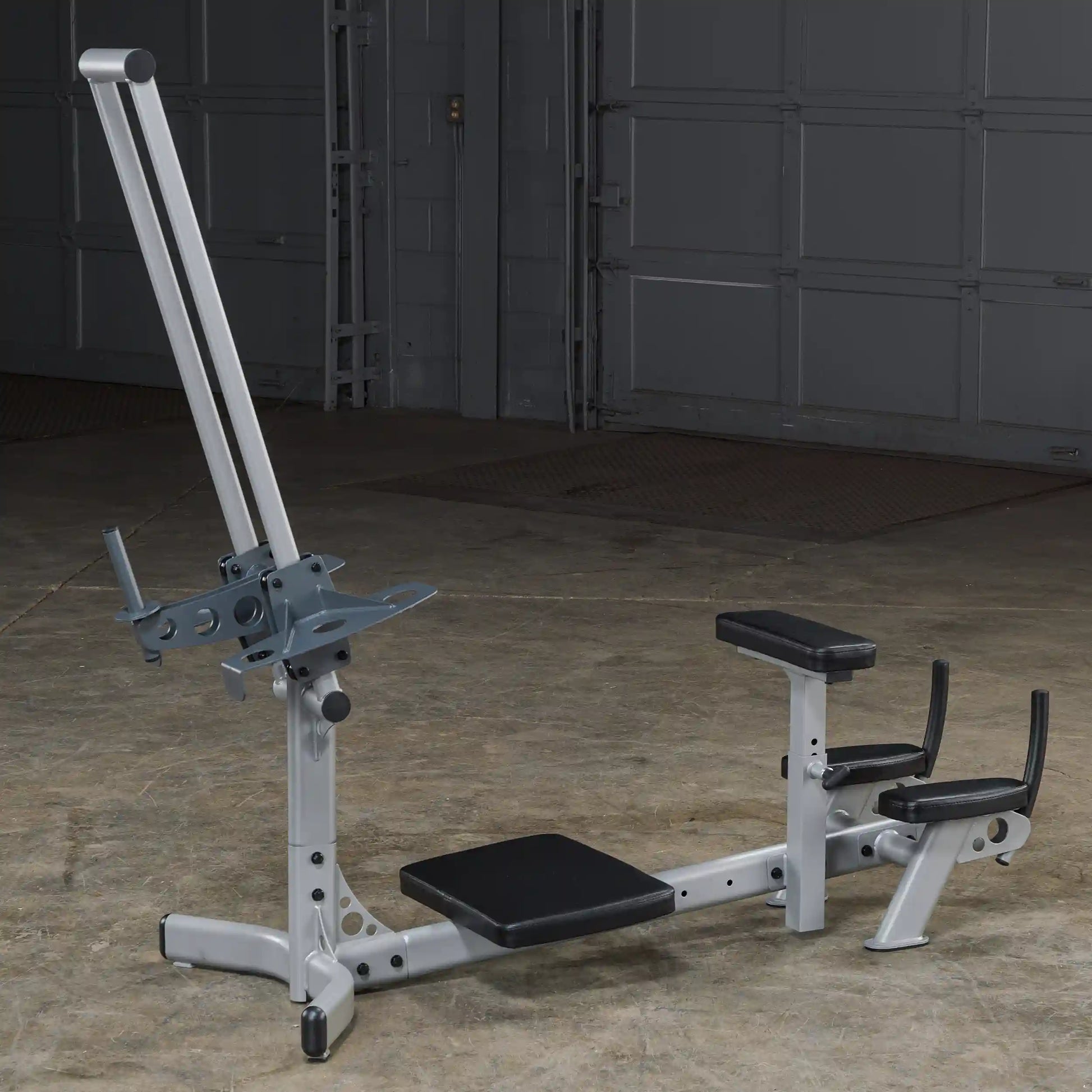A silver gym machine designed for strength training, featuring a padded seat and adjustable components, set against a gray background.