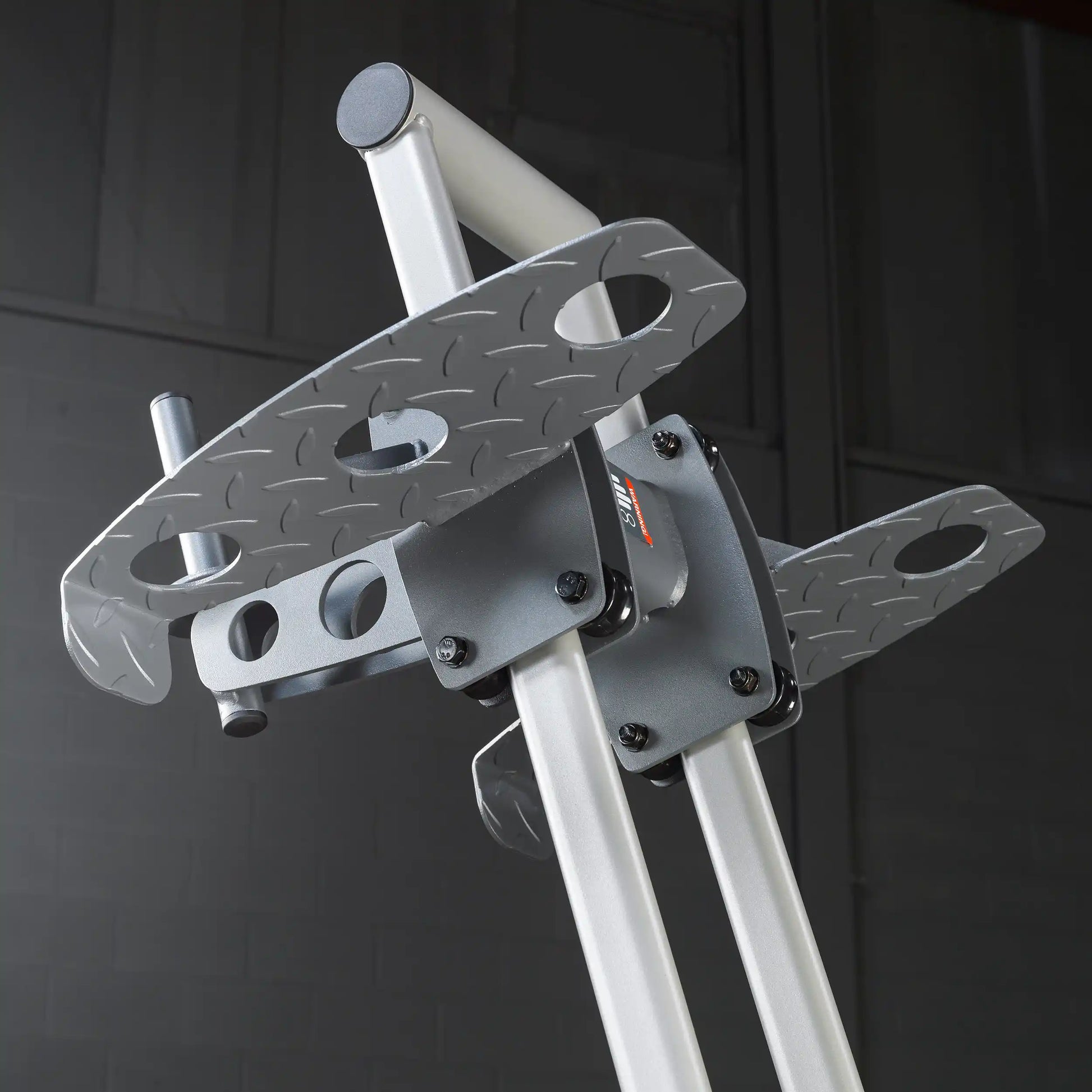Close-up view of a sturdy metal equipment stand featuring a diamond-patterned platform with multiple holes, designed for stability and support in a gym or fitness setting.