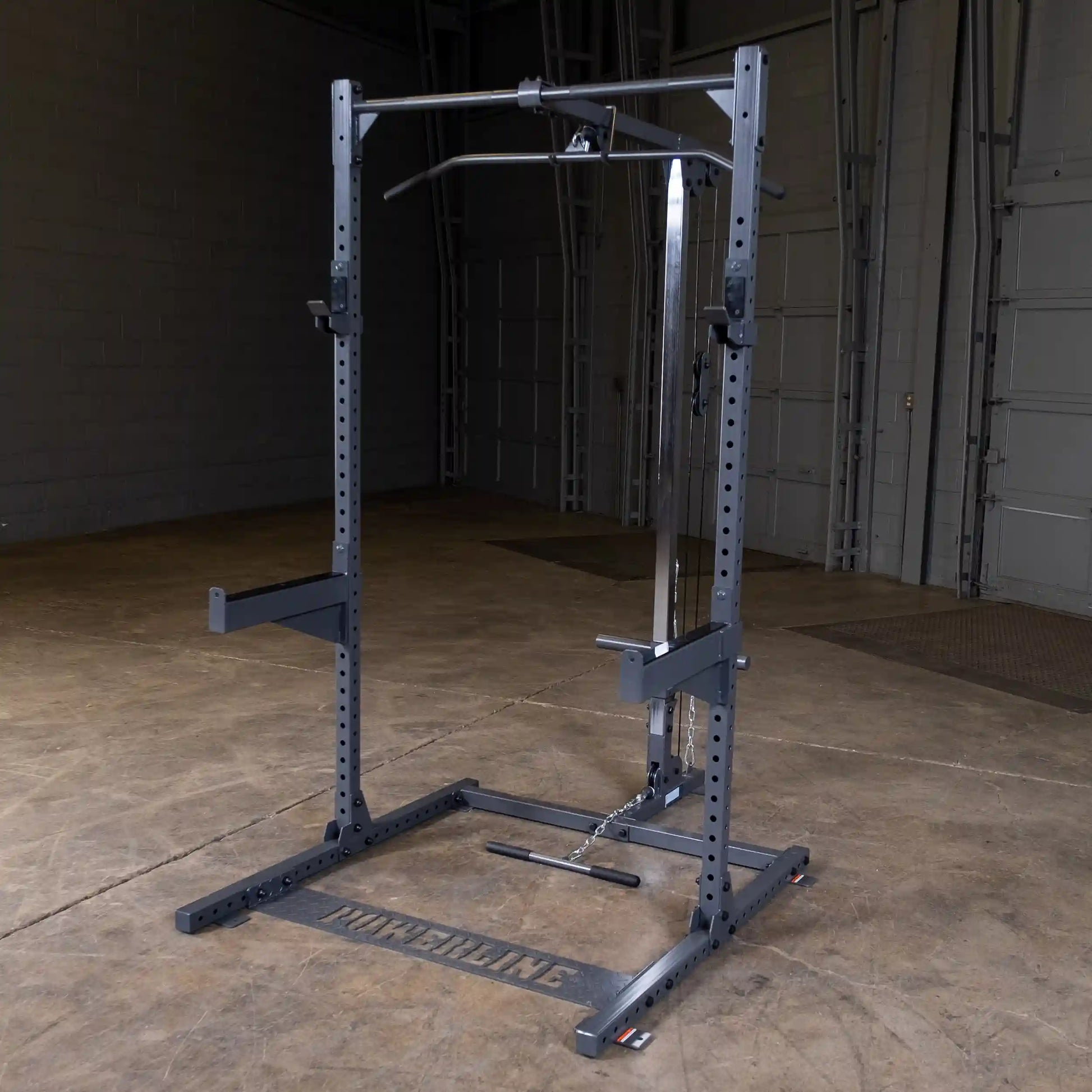 A Powerline weightlifting machine featuring a sturdy frame with adjustable pull-up and cable attachments, set in a spacious gym environment with a concrete floor and warehouse-style backdrop.