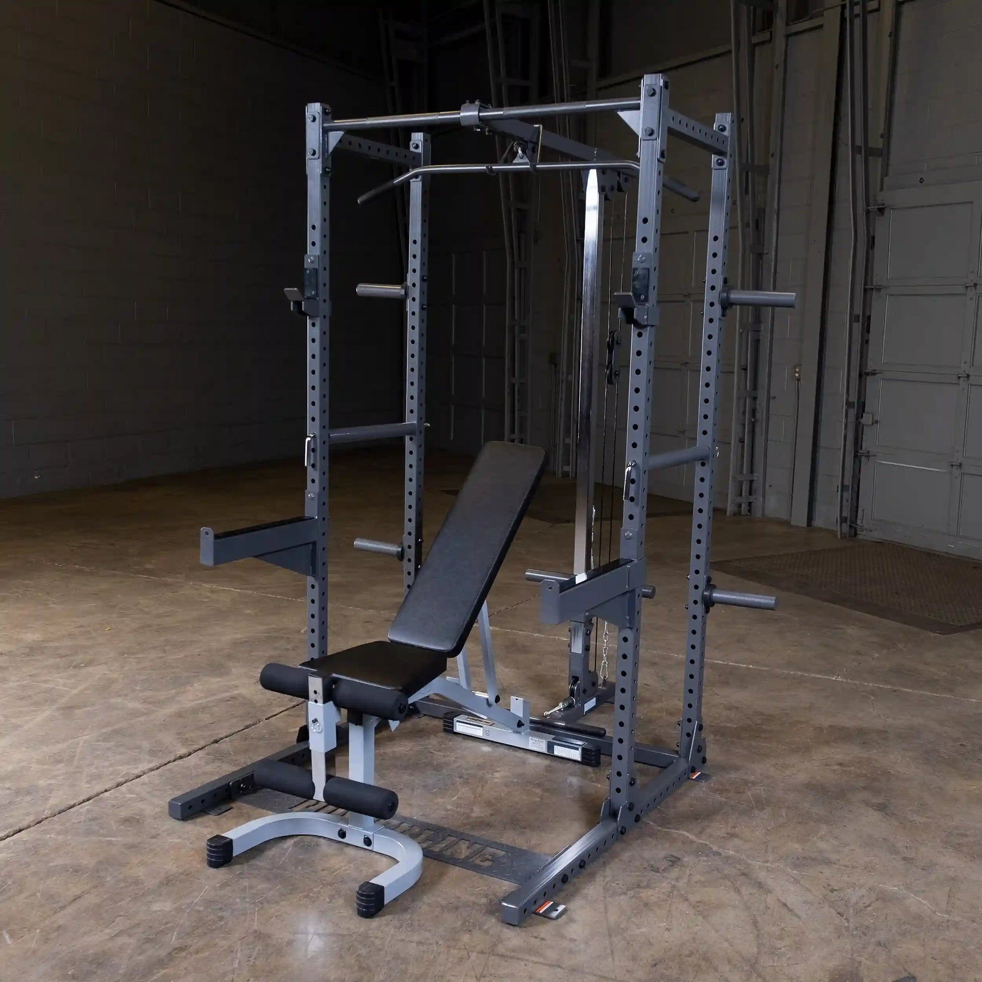 A multi-functional gym equipment setup featuring a squat rack with a pull-up bar and an adjustable bench in a spacious, empty gym environment.