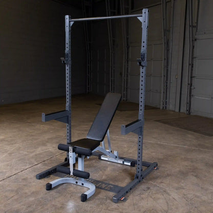 A gym setup featuring a weight bench and squat rack, positioned in a spacious, well-lit area with a concrete floor and gray walls.