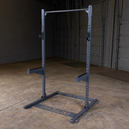 A power rack with a pull-up bar, designed for strength training, set on a concrete floor in a spacious indoor gym environment.