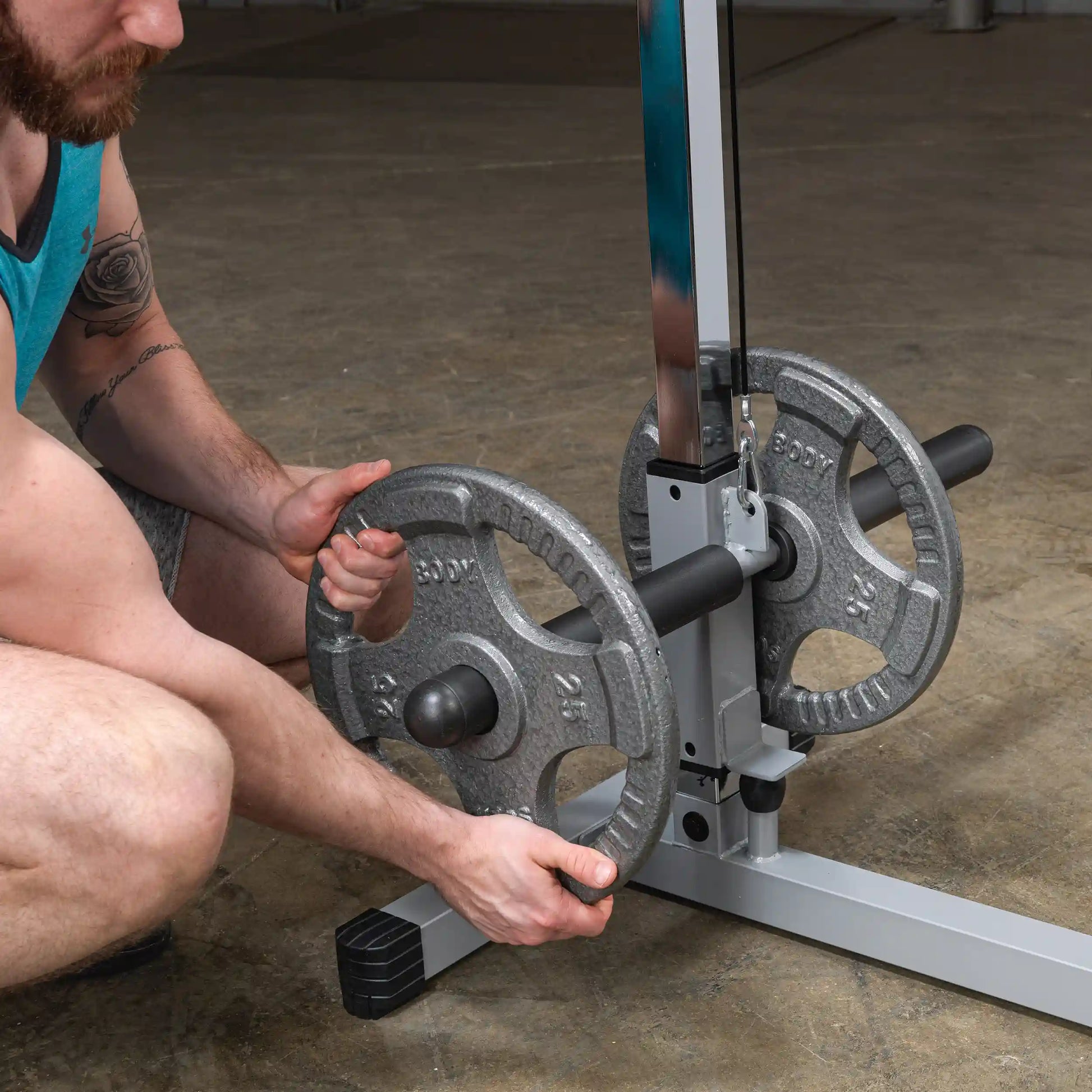 A person adjusting weight plates on a weightlifting machine in a gym setting, focusing on the hands and the equipment.
