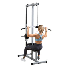 A person performing a lat pulldown exercise on a gym machine, wearing a light blue sports bra and black leggings, with a focus on their back and arms.