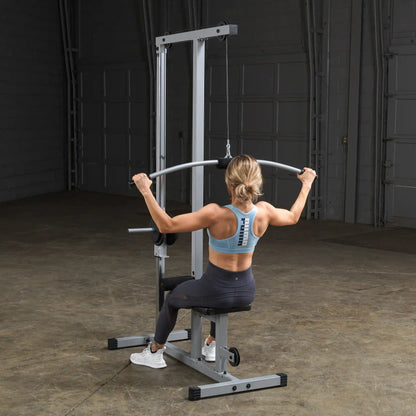 A person exercising on a lat pulldown machine in a gym, wearing a light blue sports bra and black leggings, focusing on their workout.