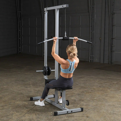 A person performing a lat pulldown exercise on a cable machine in a gym setting, wearing a blue athletic top and black leggings, with a focus on their back and arms.
