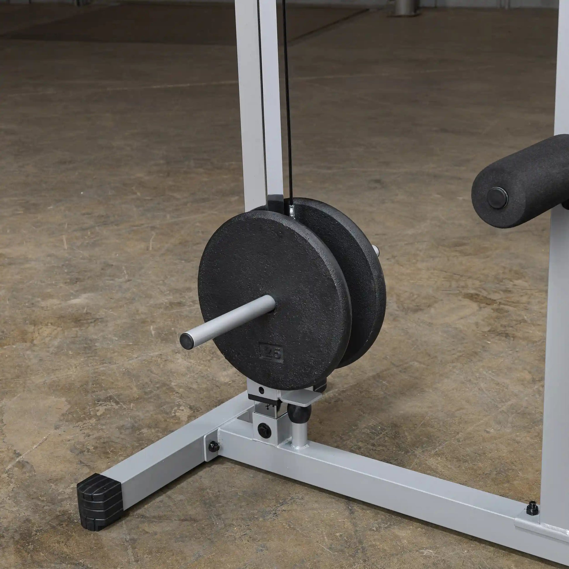 Close-up view of a weight stack on a cable machine, featuring black weight plates and a silver bar, set against a concrete floor.