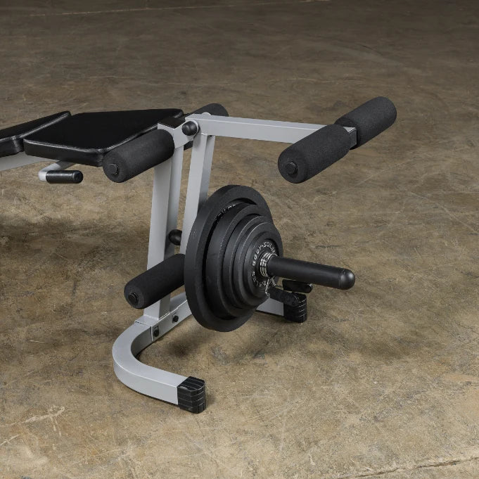 A close-up view of a weight bench with a barbell and weight plates, designed for strength training exercises, set against a textured floor background.