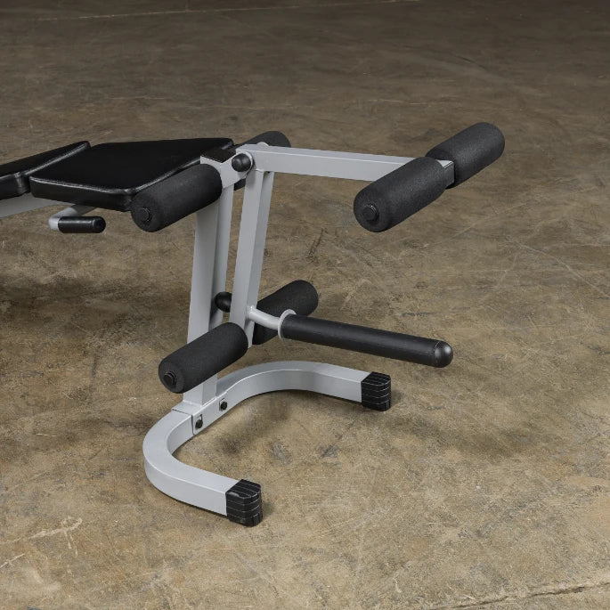A close-up view of a weight bench with padded supports and a sturdy metal frame, set against a textured concrete floor.
