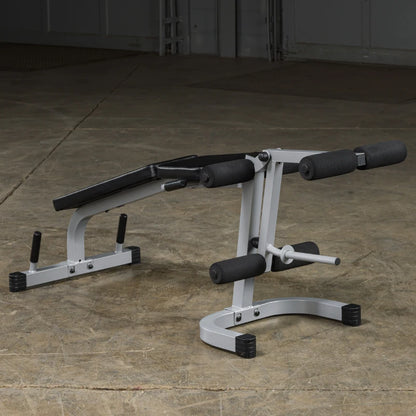 A gray and black workout bench designed for strength training, featuring padded supports and adjustable components, set on a concrete floor.