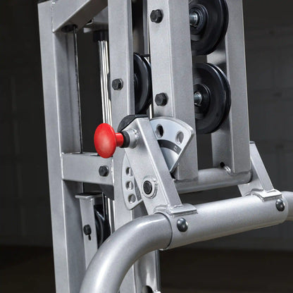 Close-up view of a weight machine pulley system, featuring a red adjustment knob and metallic components, set against a dark background.