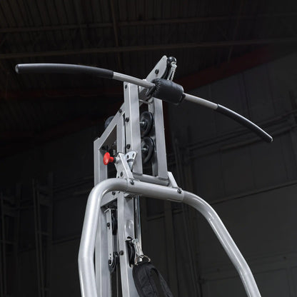 Close-up of a gym machine's pulldown bar, featuring a textured grip and a metal frame with pulleys, set against a dark background.
