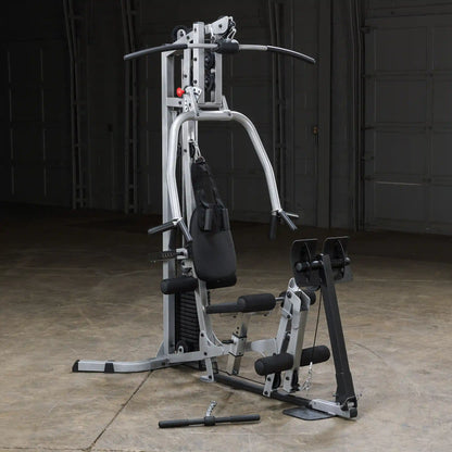 A multi-functional home gym equipment featuring a weight stack, adjustable seat, and various handles for strength training exercises, set against a neutral backdrop.