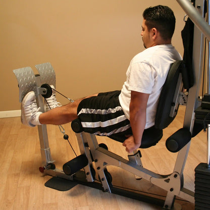 A man in a white t-shirt and black shorts performing leg exercises on a gym machine, focusing on strength training.