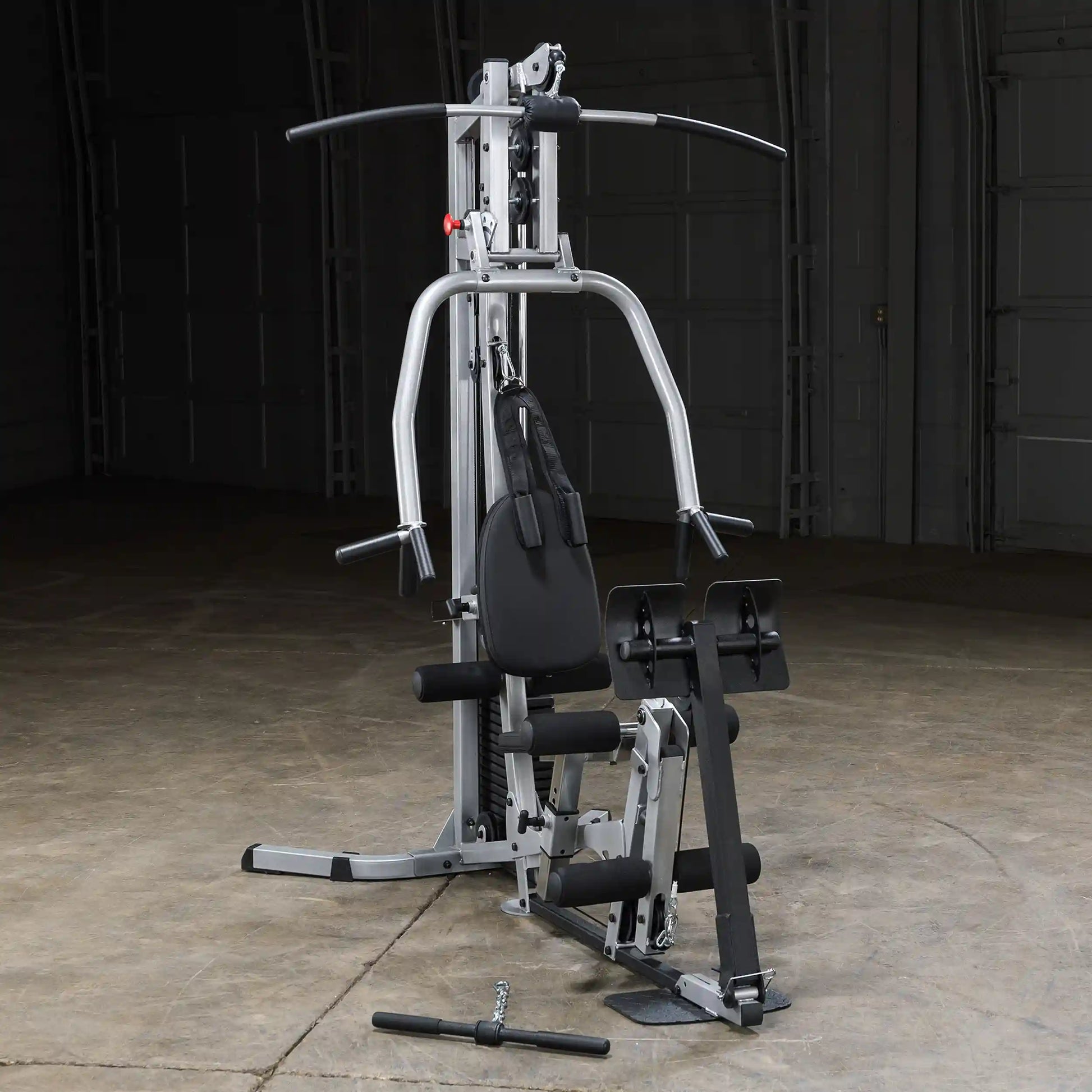 A multi-functional home gym equipment featuring a padded seat, adjustable pulleys, and various accessories for strength training, set against a dark background.