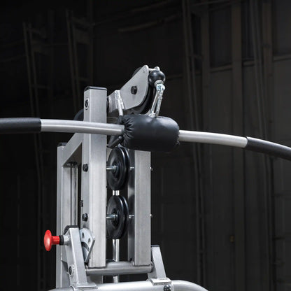 Close-up of a gym cable machine showing the pulley system, a padded handle, and a red adjustment knob, set against a dark background.