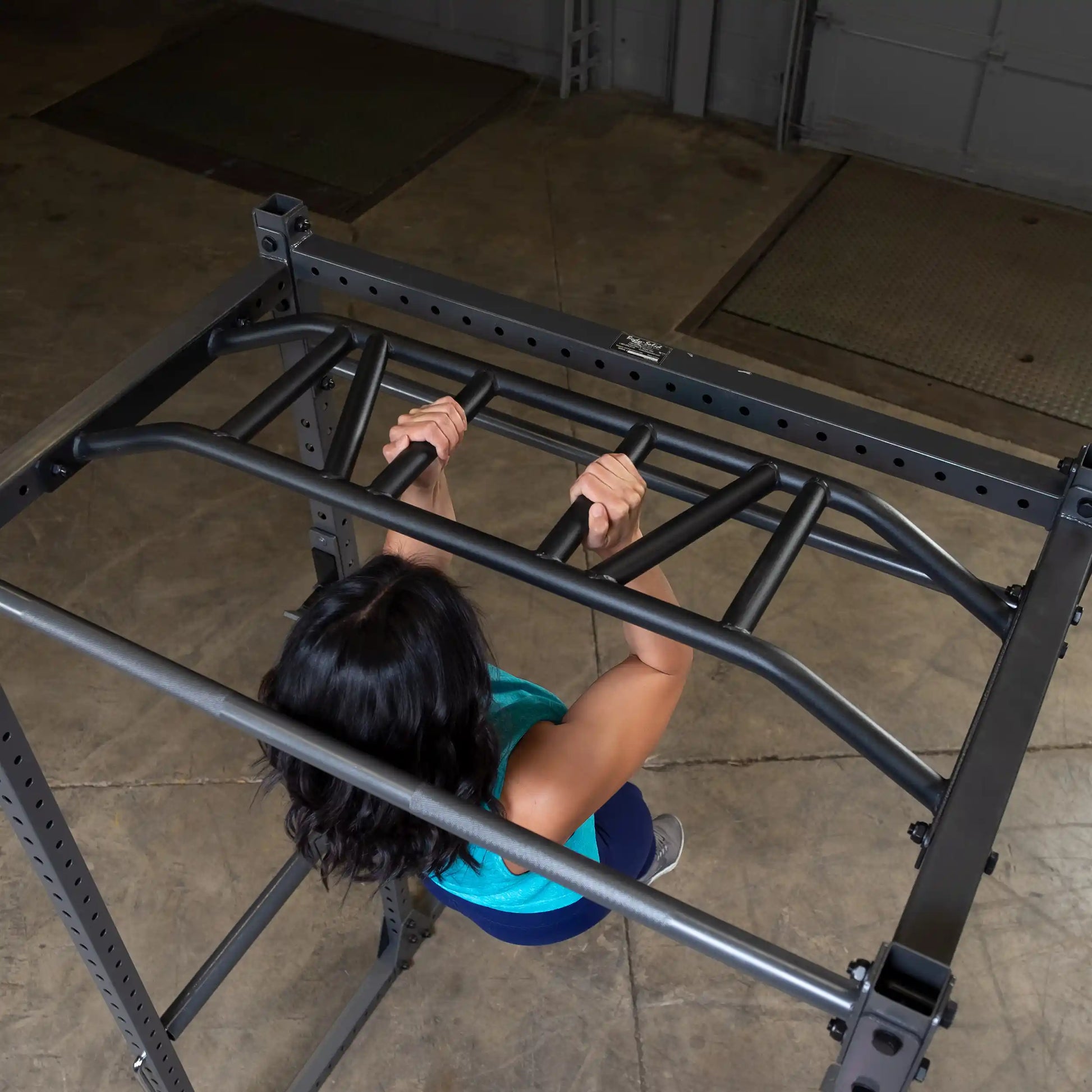 A person performing a pull-up on a metal workout rack, showcasing strength training in a gym setting.