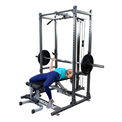 A person performing a bench press exercise on a weightlifting machine, wearing a blue tank top and leggings, with a barbell and weights positioned above them.