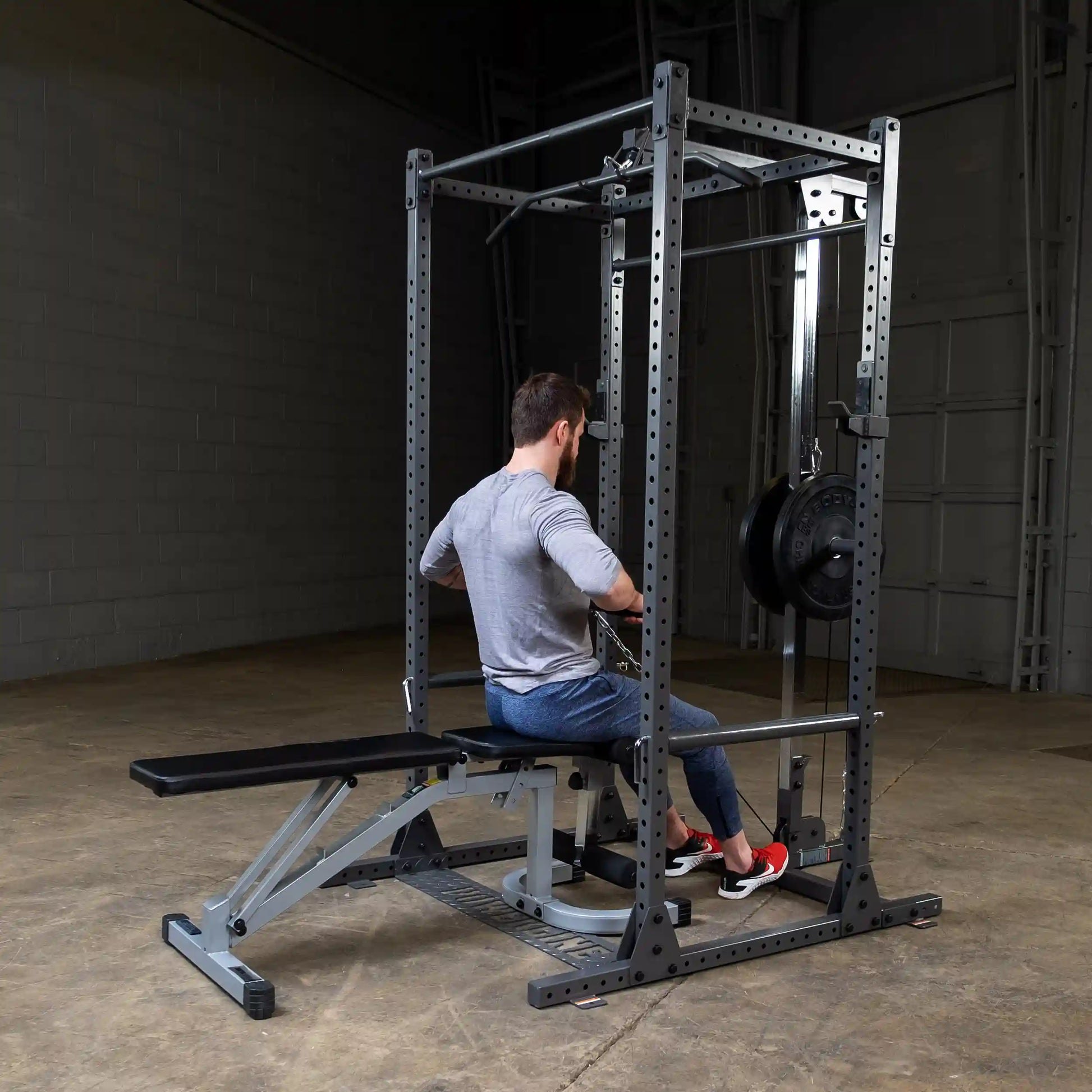 A person seated on a weight bench using a cable machine in a gym setting, with weights attached and a minimalist background.