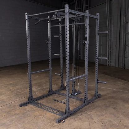 A heavy-duty gym power rack with multiple pull-up bars and adjustable weight lifting stations, set on a concrete floor in a spacious indoor gym environment.