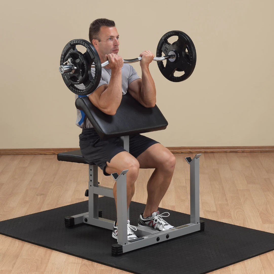 A man performing a seated barbell shoulder press exercise on a weight bench, holding a barbell with weights, in a gym setting.