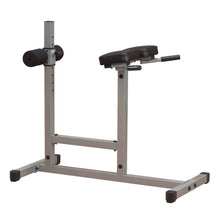 A silver weight bench with a padded seat and two black foam rollers, designed for strength training exercises.