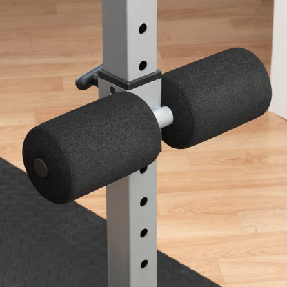 Close-up of a weightlifting barbell holder with two black foam pads attached to a silver support post, set against a wooden floor background.