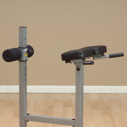 Close-up of a gym equipment bench with padded support, designed for strength training exercises, set against a neutral background.