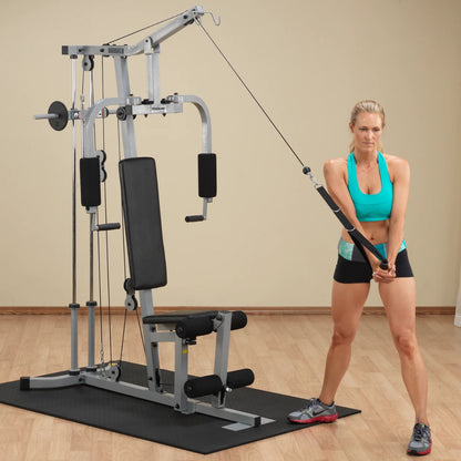 A woman in a turquoise sports bra and black shorts performing an exercise with a cable machine in a gym setting.