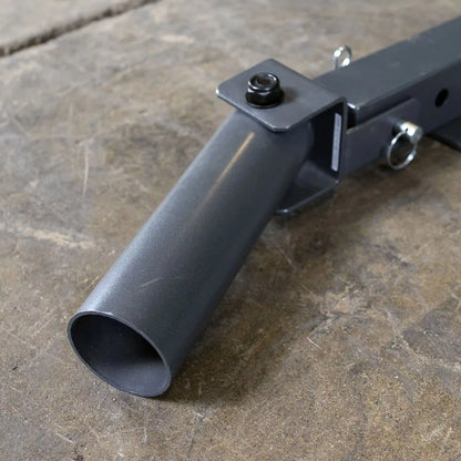 Close-up of a gray metal pipe attachment with a square mounting bracket and a bolt, resting on a textured concrete surface.